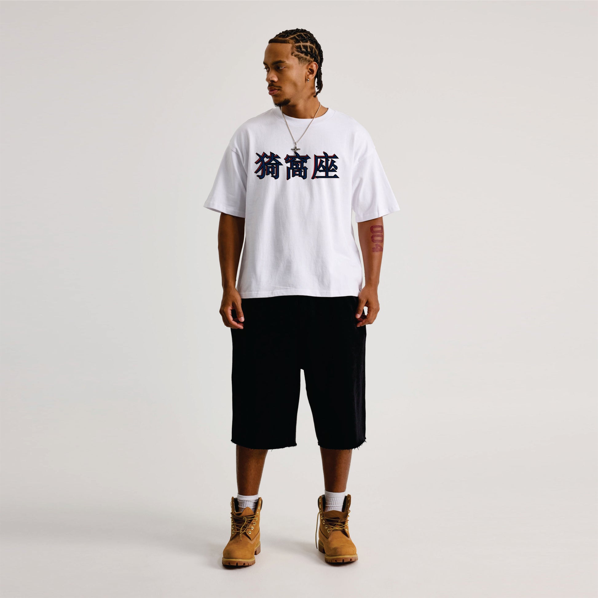 Person wearing a white t-shirt with black text, black shorts, and brown boots on a light gray background