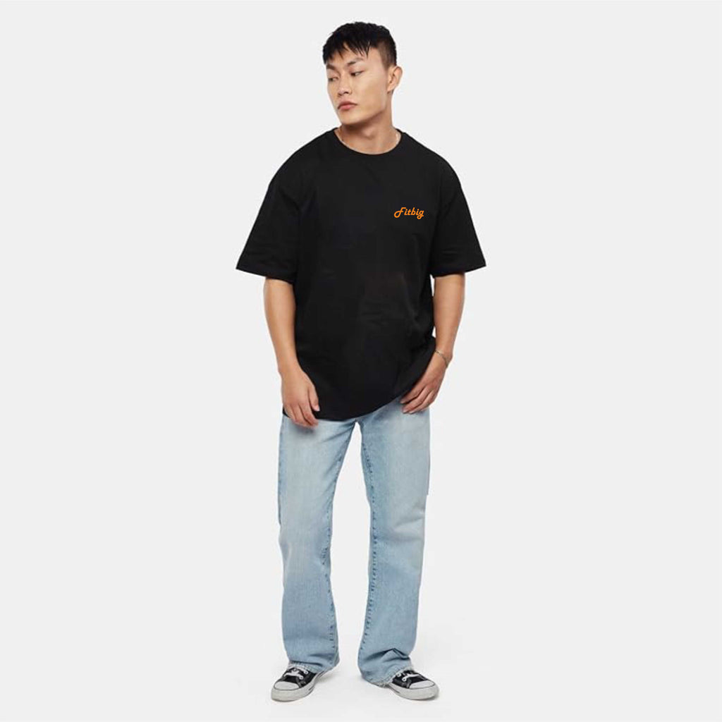 Person wearing a black t-shirt with a logo and light blue jeans on a white background