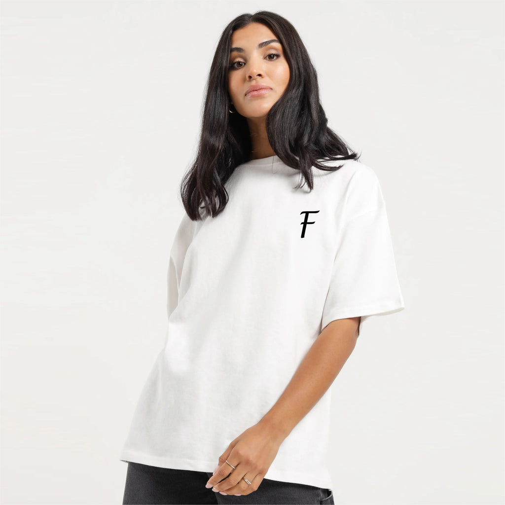 Person wearing a white t-shirt with a black letter 'F' on a plain background