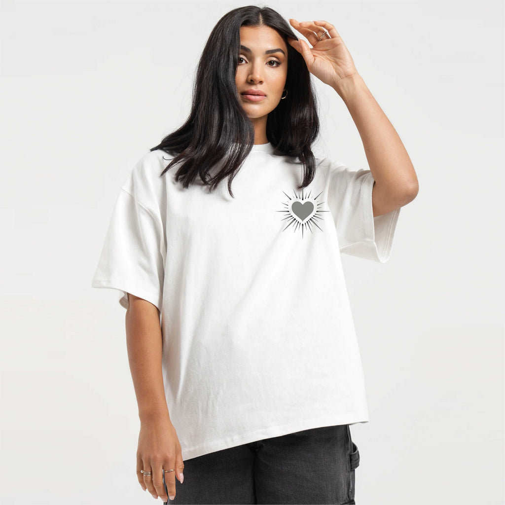 Woman wearing a white t-shirt with a heart design on a plain background