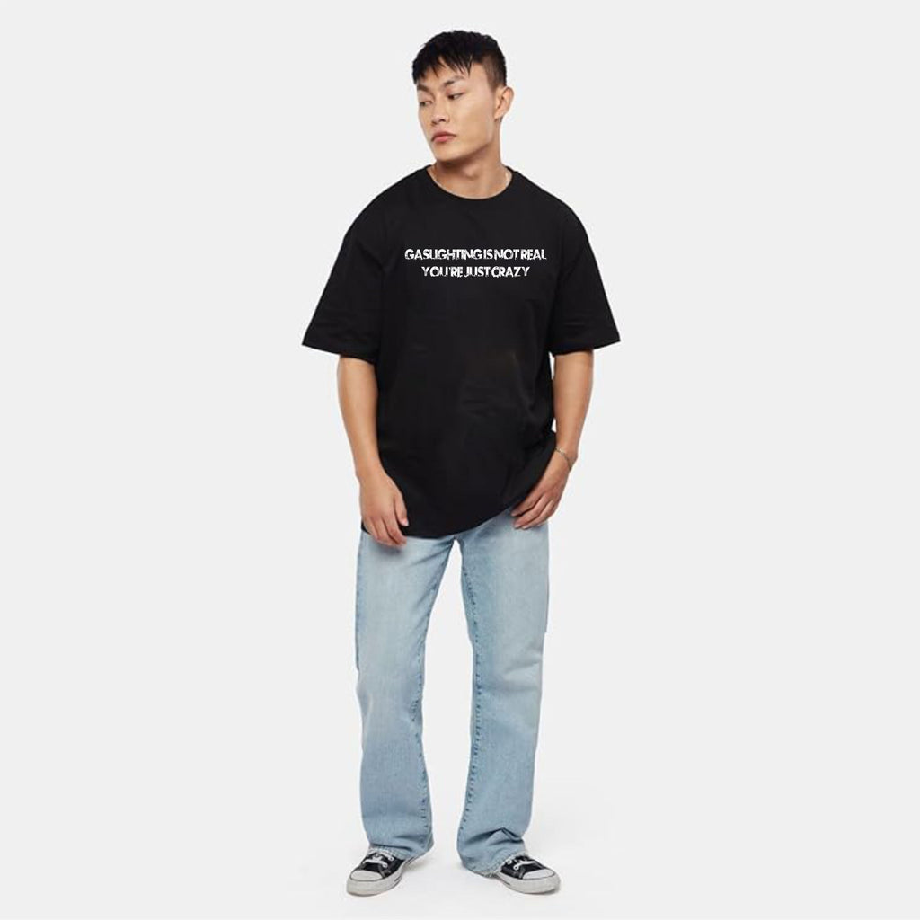 Person wearing a black t-shirt with text and light blue jeans on a white background