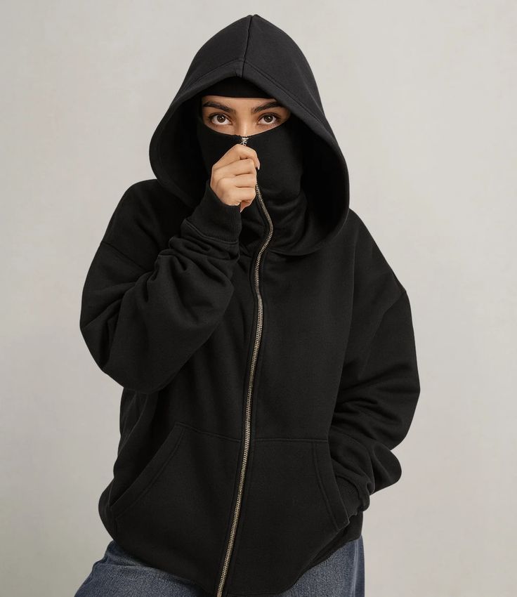 Person wearing a black hoodie with the hood up on a plain background